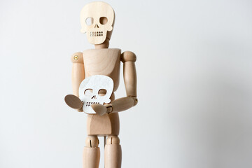 isolated mannikin with a skull mask holds a white skull