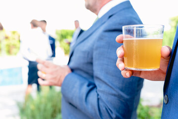 A man holds a glass with cider during a party.