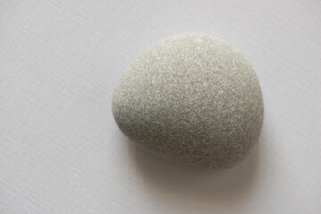 Fototapeta na wymiar smooth roundish stone on gray paper