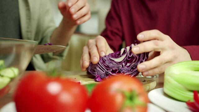 A Young Man Is Shredding A Cabbage For A Salat And Talking 