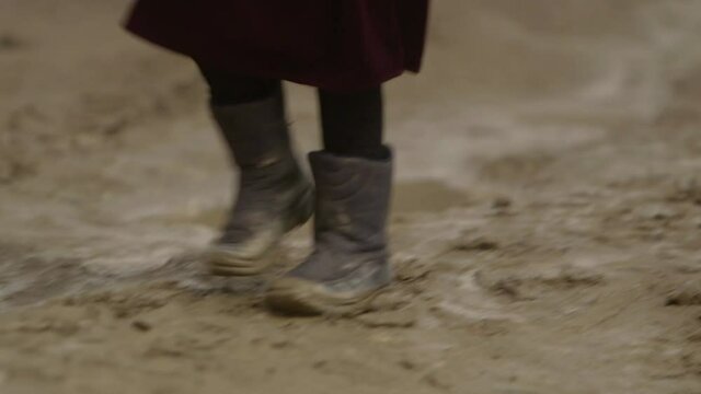 Afghanistan scene - close up of young child muddy shoes walking along a wet and muddy dirt road - Kabul city