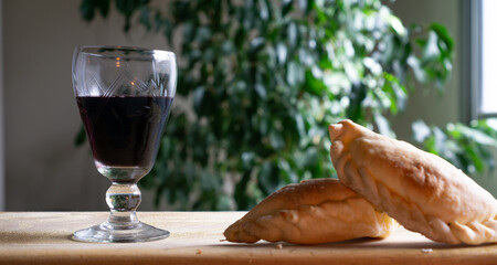 traditional Argentine food, an empanada or  patty on a wooden board and a glass of wine by its side