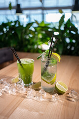 mojito with mint, lime and ice in glass and green tarkhun tarragon drink in cafe