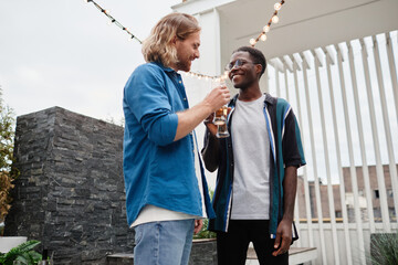 Waist up portrait of two young men chatting during outdoor party at rooftop, copy space