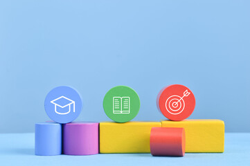 Colorful wooden blocks with graduation cap, book and dart symbols. Success concept.