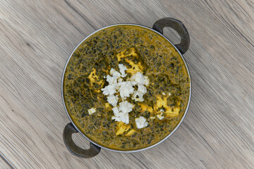Overhead view of sag paneer flavored spinach in a bowl from Indian restaurant cooked and seasoned perfectly