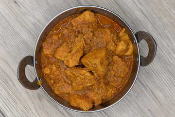 Overhead view of curry flavored chicken meat in a bowl from Indian restaurant cooked and seasoned perfectly