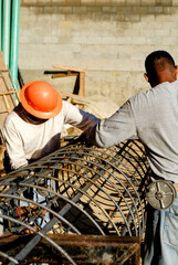 Concrete masons fabricating a large structural steel cage for a friction pile