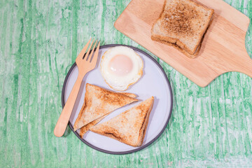 fried egg bread in plate isolated on green background close up, top view, breakfast food, and drink concept.