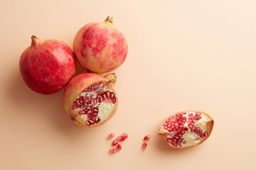 Three red pomegranate fruit isolated on pastel beige background. Top view. Flat lay pattern