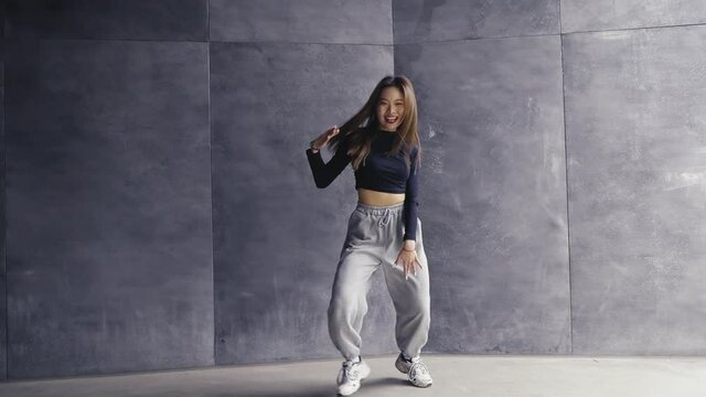 4k slow motion of young asian woman dancing against gray wall young people street dance youth culture