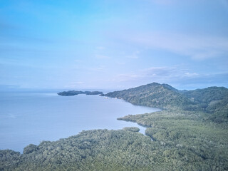 The Paquera-Puntarena ferry terminal seen in the distance surrounded by lush jungles and mountains in a drone aerial image of Paquera Costa Rica