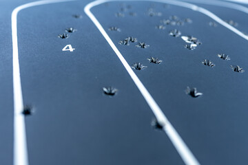 Close up shot with a shallow depth of field of a black paper silhouette target that has multiple bullet holes within in.