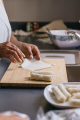 Fototapeta na wymiar Senior Asian woman making spring rolls