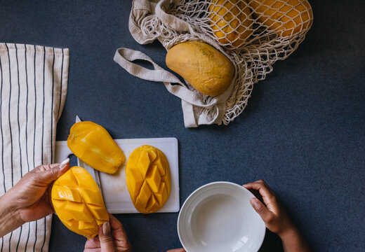 Asian grandmother cutting mango snack for grandchild