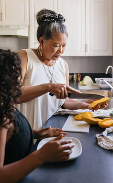 Asian grandmother making filipino mango snack for grandchild