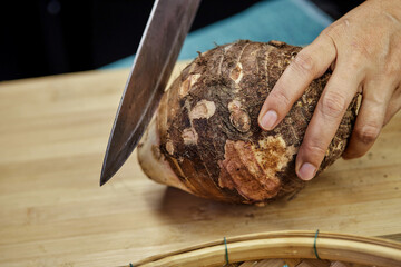 closeup human hand chopped  raw organic brown taro root
