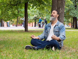 A bearded middle-aged man taking a break from the hustle and bustle of the city. He is meditating...