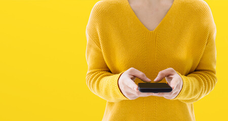 The woman in the yellow dress typed a message on her phone. The idea for copy space paste text. SMS in the application.