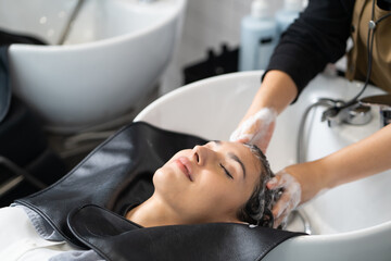 Obraz na płótnie Canvas Beautiful Caucasian women feel relax and comfortable while getting hair wash with shampoo and massage. Hair salon studio with hair stylish, beauty and fashion concept.