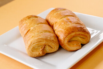 Croissant de chocolate en un plato sobre fondo amarillo, comida tradicional francesa