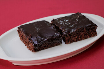 brownies de chocolate casero servido en un plato en un fondo de color rojo sin fin.