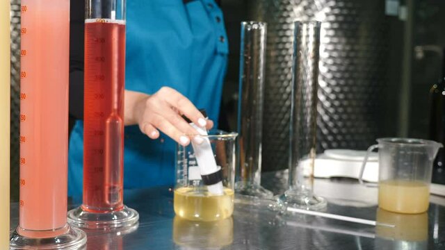Scientist pouring wine product liquid into test tube, Quality control. winemakers laboratory testing wine in winery lab. Measurement alcohol content cold stability density malic acid red grape color
