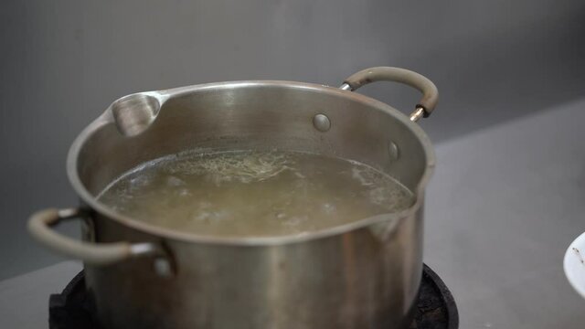 Chicken Broth soup is boiling on the gas strove with a little oil on surface of it.