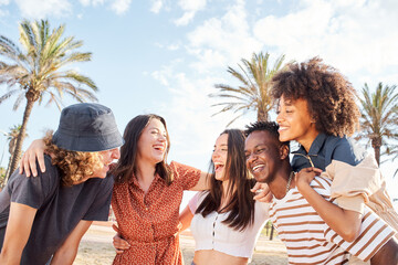 Group of young people laughing and having fun outside a beach town. Summer concept, multiethnic,...