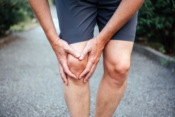 Man having having clicking or grinding sound of the kneecap due to runner's knee - obrazy, fototapety, plakaty