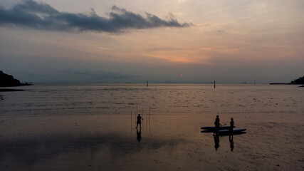 At sunset, swimmers play on the beach 