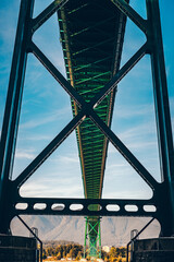 Green steel under bridge photo with blue skies