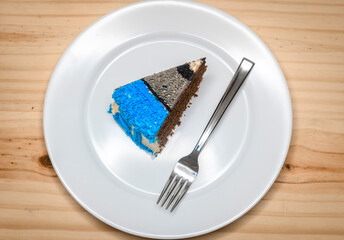 Birthday celebration with a slice of decorated chocolate cake, delicious treat with a silver fork served in a round ceramic plate overhead view.