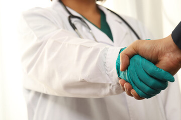 A businessman encourages the doctor by shaking his hand.