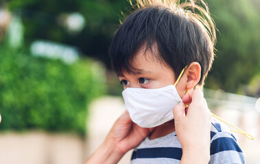 Portrait of enjoy happy love asian mother wearing protective safety mask for little asian boy son in quarantine for coronavirus with social distancing before leaving home