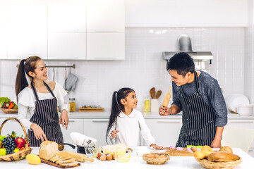 Obraz na płótnie Canvas Portrait of enjoy happy love asian family father and mother with little asian girl daughter child having fun cooking food together with baking cookie and cake ingredient on table in kitchen