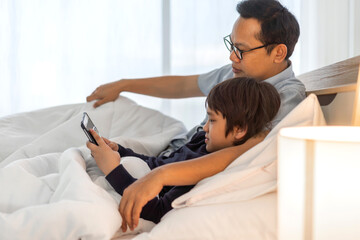 Portrait of enjoy happy love asian family father and little asian boy son smiling playing and having fun teach use tablet watching cartoon and play game at home