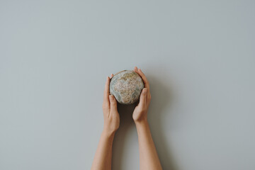 Globe model in female hands on blue background. Save the world, planet Earth concept. Women's rights and power concept