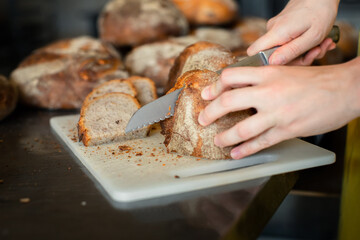 A girl cuts wheat bread on a plastic board
