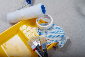 A tool for painting walls. Yellow paint tray, roller, brushes, gloves, paint tape are prepared...