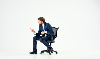 bearded man in a suit sitting in an office chair work light background