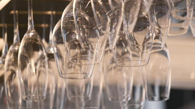 Close up empty glasses for wine above a bar rack.