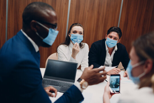 Colleagues diverse team wearing face mask office meeting. Business people men and women group conference discussion
