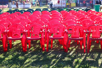 The concept of holding mass celebrations in the open air. Rows of plastic pink chairs on a sunny day, the shadow of objects.