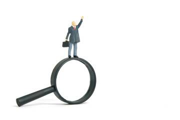 Miniature people toy figure photography. A businessman standing above magnifier glass determine to find solution. Isolated on white background.