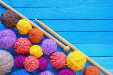 Hobbies and knitting concepts. Colorful balls of wool and  knitting needles on blue rustic table....