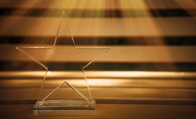 The prize for the first place is in the form of a glass star on a brown background, a ray of sun shines from the side. A clean place for the text