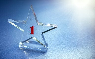 A glass star with the number one on a silver background with dew drops. Rays of sunlight from the...