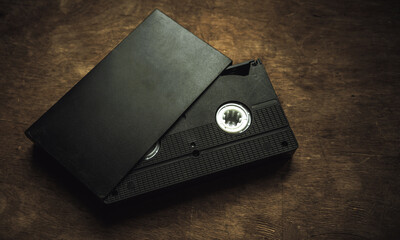 A black VHS videotape on a wooden table in a retro style. Retro recordings. Digitization of old...