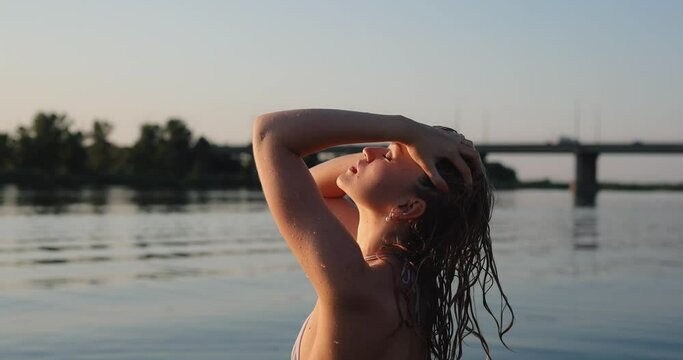 Sexy woman in mini bikini touch hair near the river, slow motion